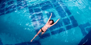 鸟瞰图的年轻女子浮在水面上的游泳池
