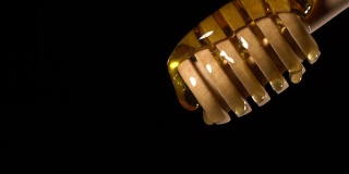 (慢镜头)蜂蜜从一个带有拷贝空间的木制蜂蜜勺中流出