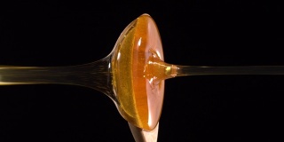 (实时和垂直)蜂蜜从木勺上掉下来