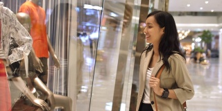 年轻的购物亚洲女人停止和看商店橱窗