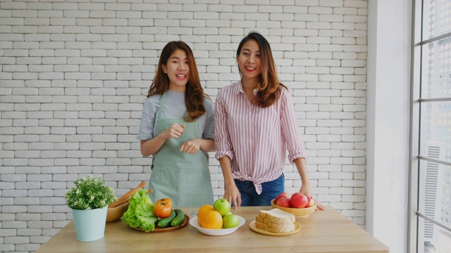 两名年轻的亚洲女性美食博主竖起大拇指，并在录制视频广播，视频博客健康的生活方式