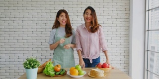 两名年轻的亚洲女性美食博主竖起大拇指，并在录制视频广播，视频博客健康的生活方式