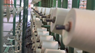 纺织厂工业整经机筒子架上的白色纱线轴视频素材模板下载