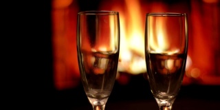 两个空酒杯的特写镜头与舒适温暖的壁炉与火焰在一个黑暗的公寓室内的背景
