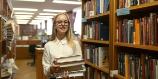 漂亮女生在大学图书馆休息。寻找必要的文学课。站在书架上。