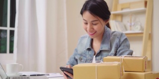 聪明的亚洲年轻企业家女企业家企业主中小企业在线检查产品库存和节省到笔记本电脑在家里工作。小企业主在家办公的概念。