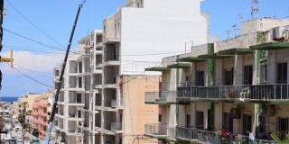 Qawra,马耳他14所示。2019年5月——工地上的建筑工人，用升降机在顶层举起水泥袋