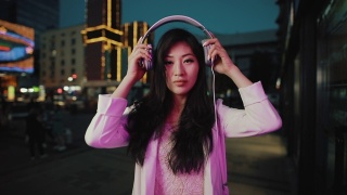 亚洲女人晚上戴上耳机视频素材模板下载