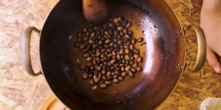 慢镜头近距离拍摄用木勺在平底锅里烘焙新鲜咖啡豆，准备自制咖啡