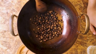 慢镜头近距离拍摄用木勺在平底锅里烘焙新鲜咖啡豆，准备自制咖啡视频素材模板下载