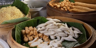 用餐时的各种亚洲菜碗。木制碗与各种传统泰国菜出售放置在街头餐馆的摊位在城市。