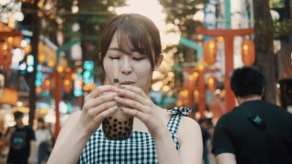 年轻的亚洲女子在西门町购物区喝珍珠奶茶视频素材模板下载