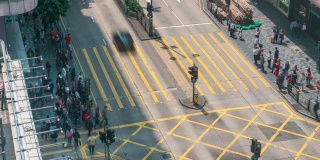 在中国香港尖沙咀地区，人们和出租车穿过一个非常繁忙的十字路口