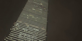 商业办公大楼与夜间照明在现代城市从下面看。现代城市中心的高层商业摩天大楼和高层办公大楼。运动时摇晃摄像机