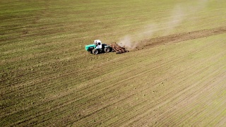 无人机拍摄的农民在拖拉机上使用大型耕作机在田间犁地播种视频素材模板下载