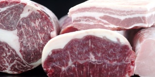 将9夹不同类型的新鲜生猪肉和牛肉放在厨房昏暗的桌子上切片。