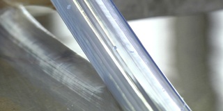 在工厂生产透明硅胶管。在机床上用水制造塑料管的过程。用热水冷却软管。软管被拉过滚筒。