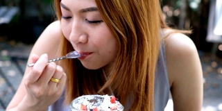 4K拍摄:特写亚洲女人的嘴正在咖啡馆吃奶油蛋糕