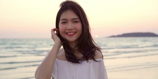 年轻的亚洲女人在海滩上感到快乐，美丽的女性快乐放松微笑在海滩附近的海边当日落在傍晚。生活方式女性旅行海滩概念。