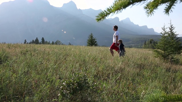 Father and young son hike through mountain meadow