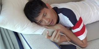 年轻的亚洲商人使用智能手机玩手机游戏，放松与网上购物在他的职业