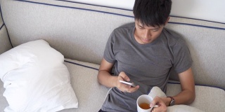 年轻的亚洲商人使用智能手机玩手机游戏，放松与网上购物在他的职业