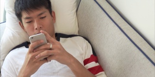年轻的亚洲商人使用数码平板电脑和智能手机在家里工作，并在他的职业生涯中通过网上购物放松
