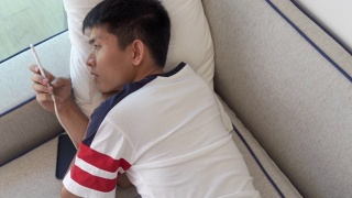年轻的亚洲商人使用智能手机玩手机游戏，放松与网上购物在他的职业视频素材模板下载