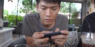 年轻的亚洲商人使用数码平板电脑和智能手机在家里工作，并在他的职业生涯中通过网上购物放松