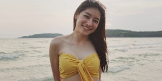 年轻的亚洲女人在海滩上感到快乐，美丽的女性快乐放松微笑在海滩附近的海边当日落在傍晚。生活方式女孩旅游度假夏季概念。慢动作镜头。