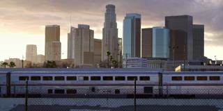 慢动作的乘客列车在洛杉矶市中心的城市天际线在夕阳下