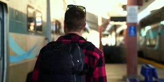 慢镜头:美丽的年轻男性背包客走在洛杉矶火车站的站台上