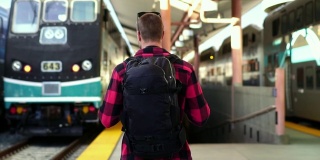 慢镜头:美丽的年轻男性背包客走在洛杉矶火车站的月台上。