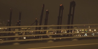 夜间驶过修海港的城市高速公路上行驶的汽车晃动射击。从窗口开车到海港的工业船厂和现代城市的建筑