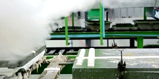 在橡胶枕厂的传送带上，用热蒸汽将金属乳胶枕模具从机器上移出