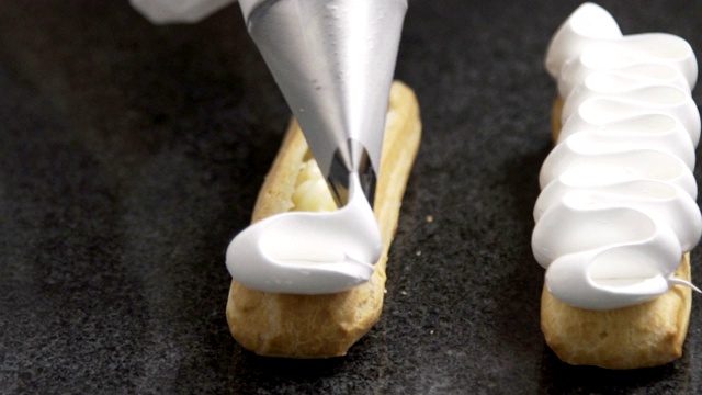 糕点师将奶油涂在美味的泡芙上