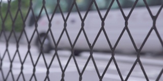 汽车在城市道路上通过栅栏网。在现代城市的高速公路上，通过钢丝网观察汽车和出租车的行驶情况