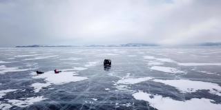 在俄罗斯阳光明媚的冬日里，无人机拍摄的汽车在美丽的深蓝色冰纹理冰冻的贝加尔湖表面上行驶的鸟瞰图
