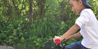 亚洲小男孩在花园里学骑和摔倒自行车，学骑自行车