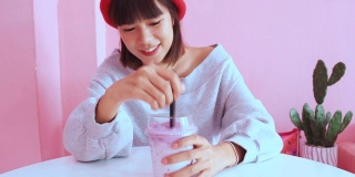年轻的亚洲千禧一代女性在粉色柔和的咖啡馆喝冰珍珠奶茶