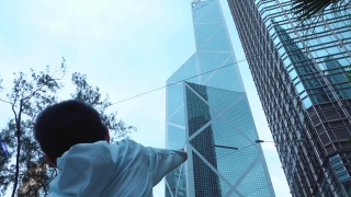 可爱的男孩指着香港的摩天大楼视频素材模板下载