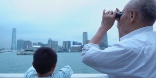 爷爷和孙子用望远镜看香港的天际线