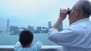 爷爷和孙子用望远镜看香港的天际线视频素材模板下载