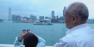 爷爷和孙子用望远镜看香港的天际线