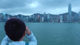 亚洲男孩用双筒望远镜看香港的建筑视频素材模板下载