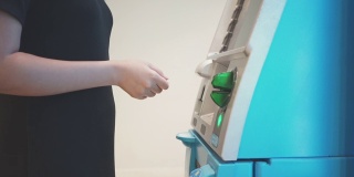 在自动取款机上插入银行卡取钱并输入密码的女子。使用自动提款机的女人。