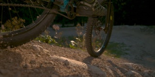 近距离镜头:阳光照耀在沙砾小路上，作为下坡自行车骑过相机。