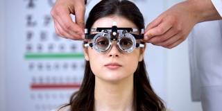 眼科医生将光学试验架放在女孩视力矫正屈光度测量上