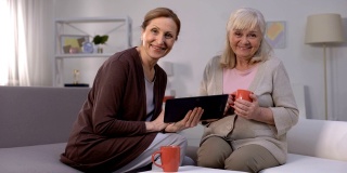 老年妇女微笑着，在平板电脑上看娱乐节目，快速互联网