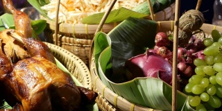 装烤鸡和水果的篮子。在传统的泰国街头餐馆的摊位上放置着美味的炸鸡和新鲜水果编织篮子。
